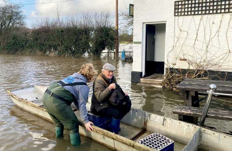 Regular drinkers get ferried to a pub cut off by deep flood waters