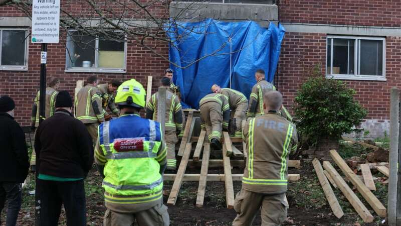 A man weighing nearly 50st had to be pulled to safety down a ramp after fire fighters knocked down a wall (Image: UkNewsinPictures)