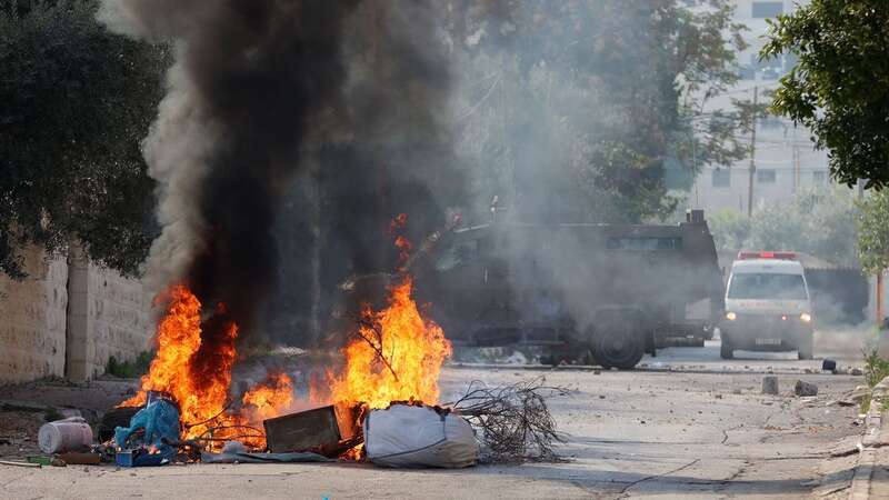 An ambulance drives past an Israeli military vehicle (Image: AFP via Getty Images)