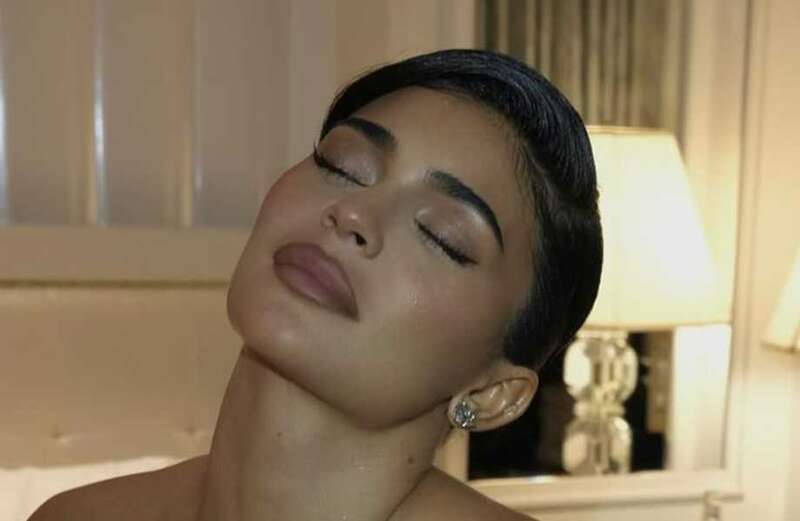 Kylie flaunts her signature NSFW pose and pours out of plunging black gown