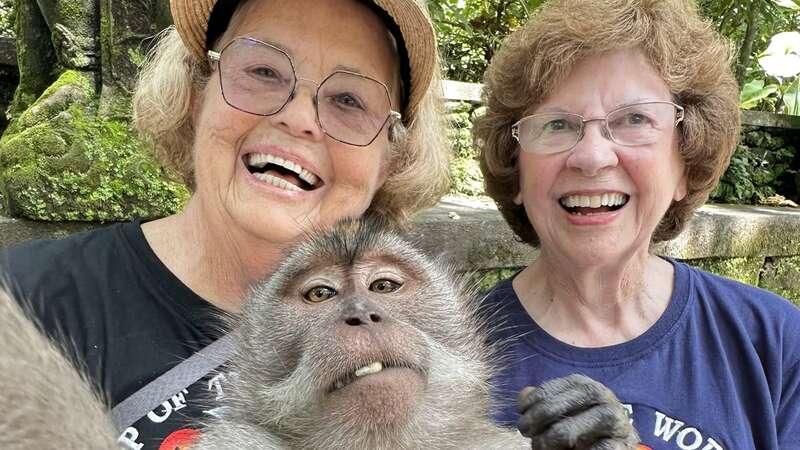 Sandy and Ellie pose with a monkey in Bali (Image: Around the World at 80 / SWNS)