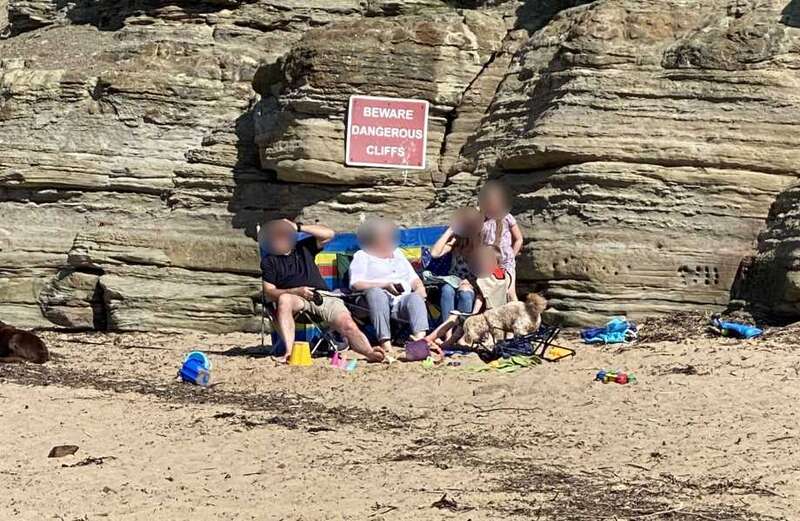 'Idiotic' beachgoers sunbathe under killer cliffs - ignoring huge danger sign