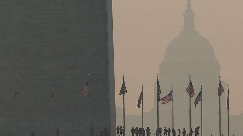 Tourists walk around the base of the Washington Monument as wildfire smoke casts a haze in the capital (Image: Getty Images)