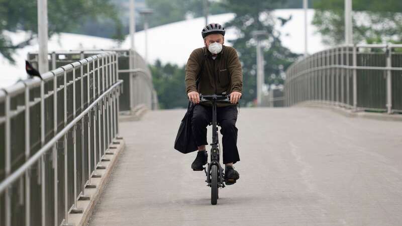 A person bikes on Adàwe Crossing Bridge in Ottawa as wildfire smoke engulfs the region on Wednesday, June 7, 2023. (Image: AP)