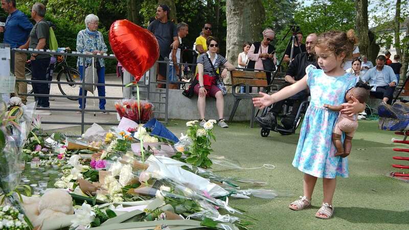 A young child near tributes left near the scene at a lakeside park in Annecy, France (Image: PA)