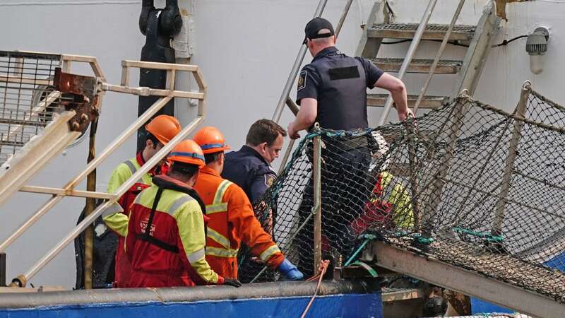 Police officers speak to crew members onboard the Polar Prince, the main support ship for the Titan submersible, at the Port of St. John