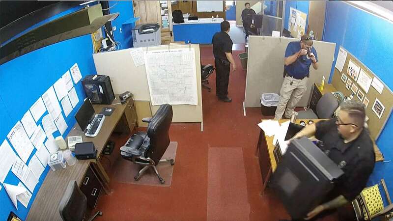 The surveillance video shows Marion Police Department confiscating computers and cellphones from the publisher (Image: AP)