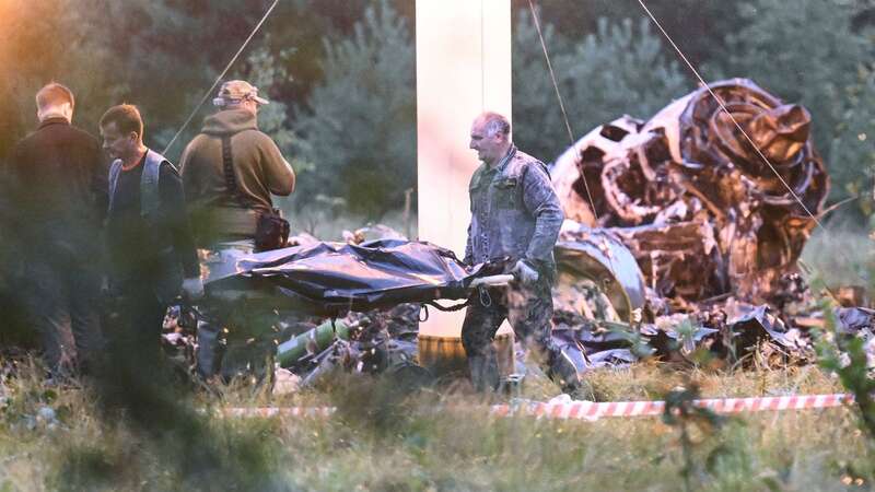 Workers take bodies from the wreckage (Image: AP)