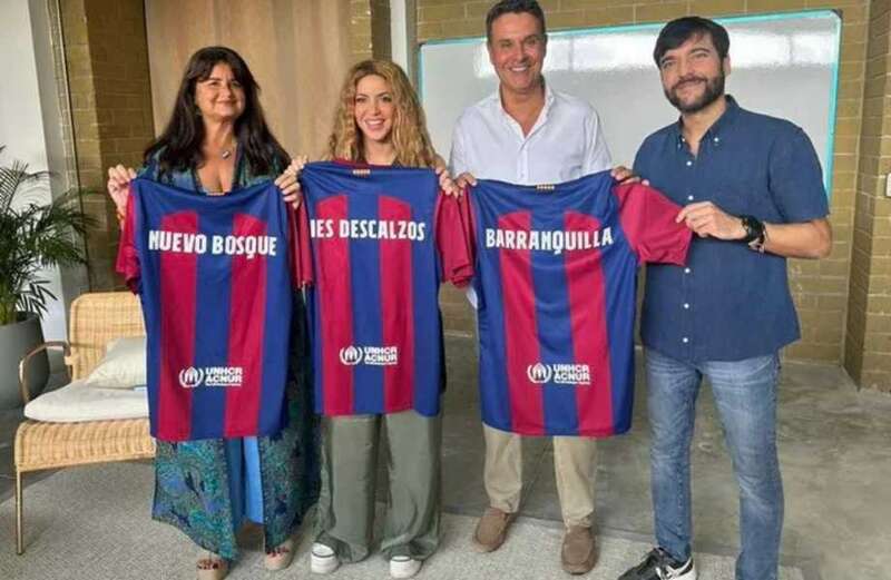 Shakira holds up Barcelona shirt as she poses with staff from Pique's ex-club