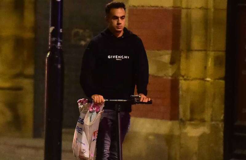 Reguilon carries Tesco bag full of flowers as he rides on electric scooter