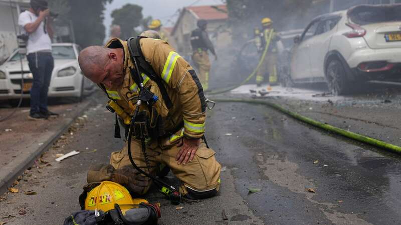 An Israeli firefighter kneels to compose himself (Image: AP)