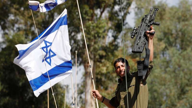 An Israeli soldier gestures as he rides on a military vehicle (Image: AFP via Getty Images)