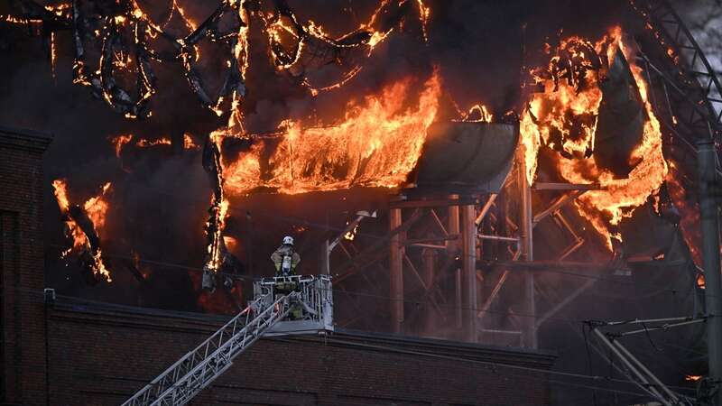 A firefighter is seen on an aerial ladder platform as a fire engulfs a structure of the Oceana Waterworld (Image: TT News Agency/AFP via Getty Ima)