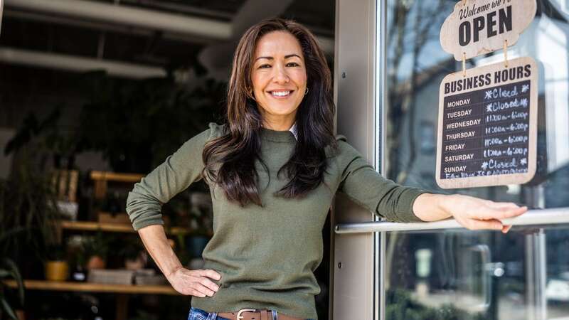 Portrait of proud female flower shop owner in front of open sign (Image: Getty Images)