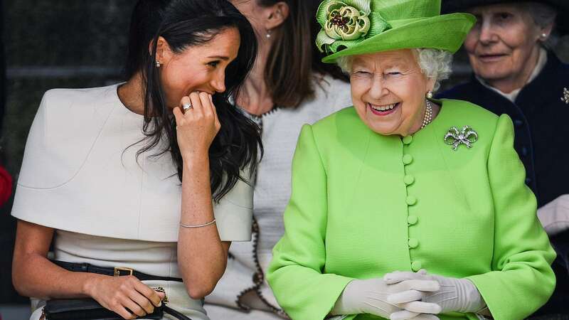 Queen Elizabeth II sits and laughs with Meghan, Duchess of Sussex, at an event in 2018 (Image: Getty Images)