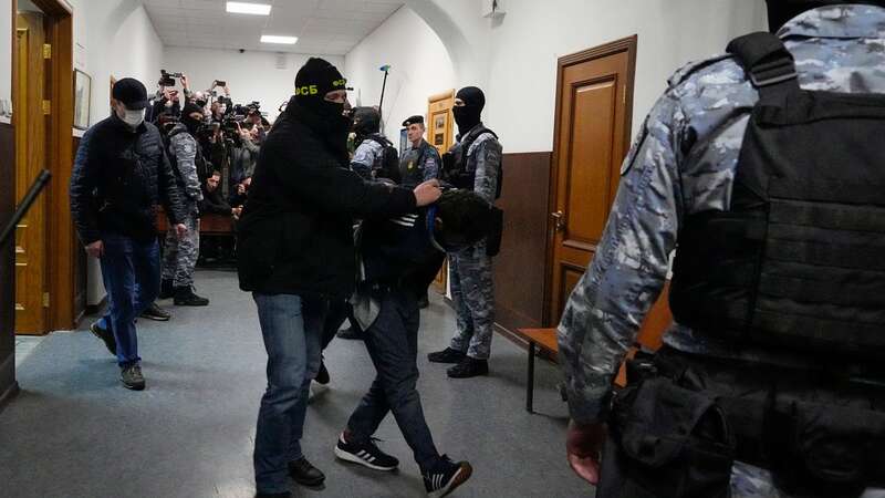 A suspect in the Crocus City Hall shooting on Friday, is escorted by police officers in the Basmanny District Court in Moscow (Image: Copyright 2024 The Associated Press. All rights reserved.)