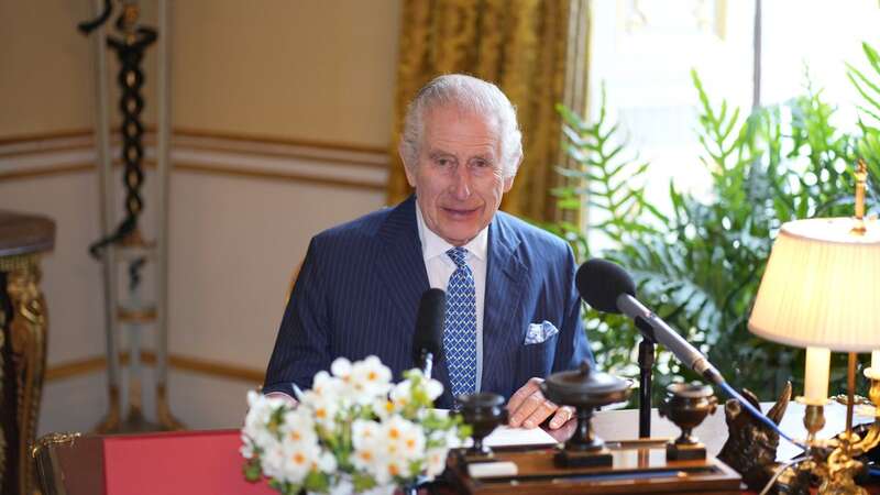 King Charles pictured sitting at his desk in Buckingham Palace’s 18th Century Room as he recorded his message (Image: PA)