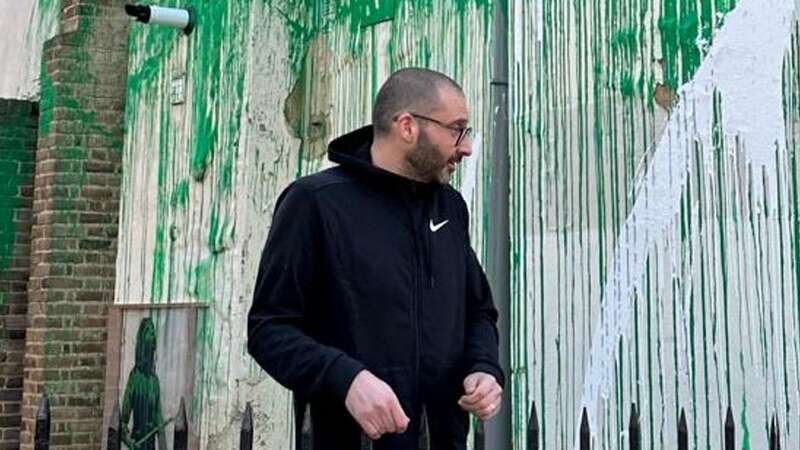 A man believed to be elusive artist Banksy at the site of his latest mural (Image: SWNS)