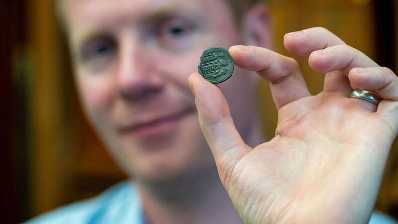 Professor Rory Naismith holding a Byzantine silver coin in the Fitzwilliam Museum (Image: Adam Page/SWNS)