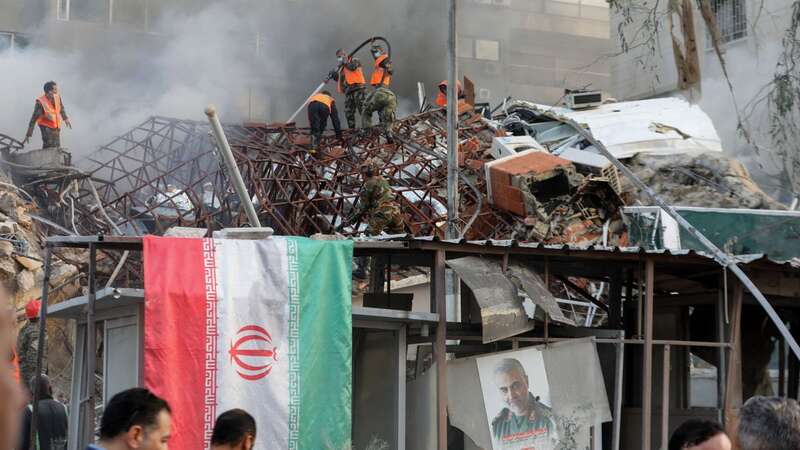 Emergency and security personnel extinguish a fire at the site of strikes which hit a building annexed to the Iranian embassy in Syria