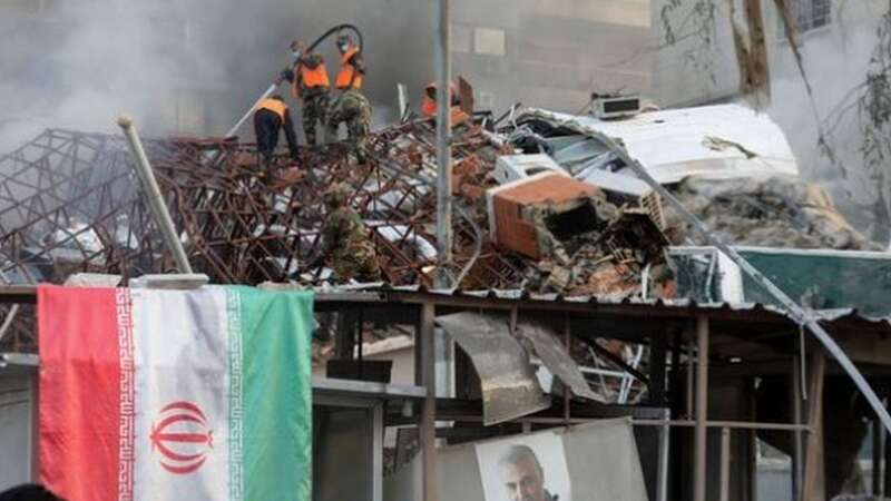 Emergency and security personnel extinguish a fire at the site of strikes which hit a building annexed to the Iranian embassy in Syria