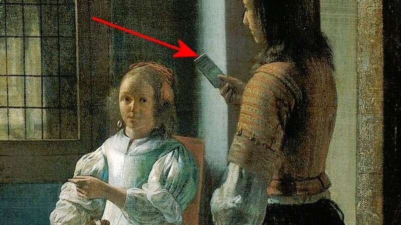 This 17th century painting by Dutch painter Pieter de Hooch appears to show a man holding what some people think is a smartphone - despite the devices not being invented for another 250 years (Image: Universal Images Group via Getty Images)