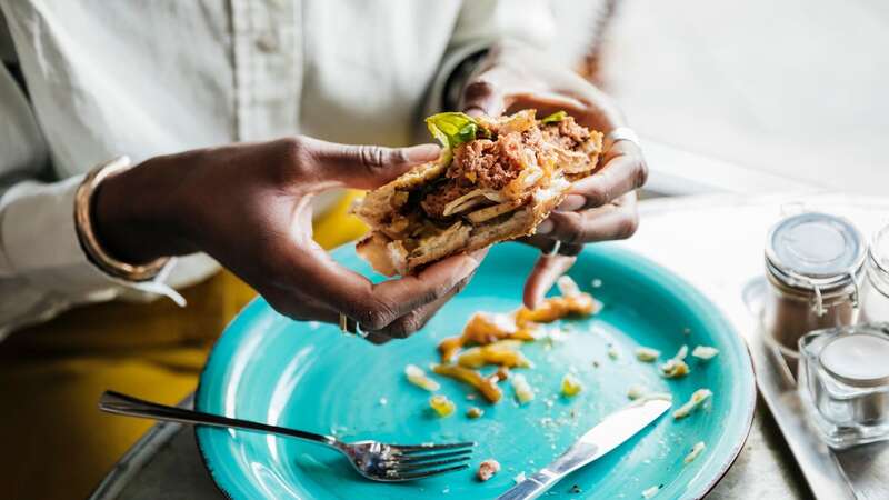 A woman eating a vegan burger [file image] (Image: Getty Images)