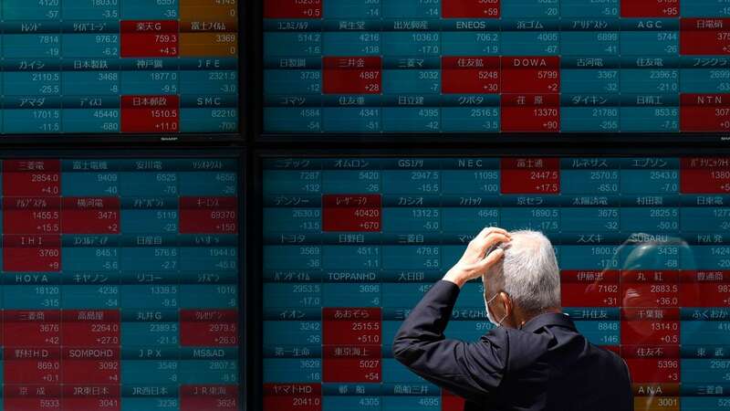 A trader looks at an electronic stock board showing Japan