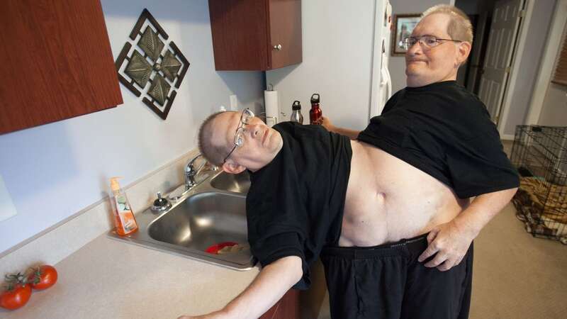 Donnie, left, and Ronnie Galyon, walk to get water inside their home (Image: AP)