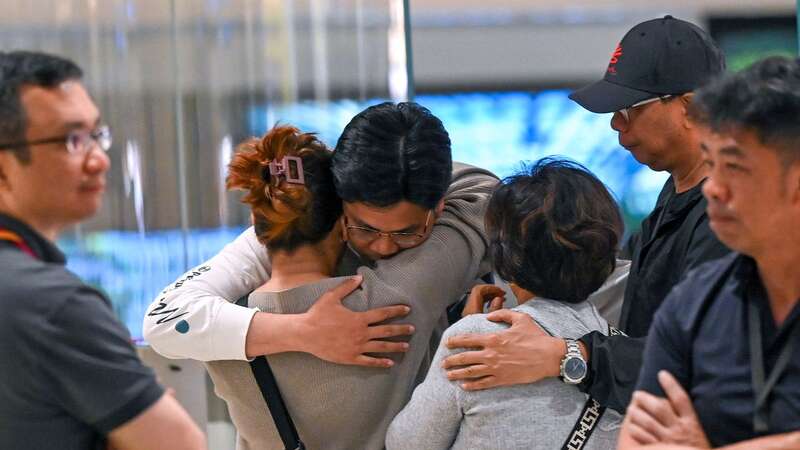 Relieved Singapore Airlines passengers hug loved ones after safely landing (Image: AFP via Getty Images)