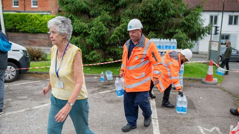 Residents taking bottled water from collection points in Bramley, Surrey (Image: Tony Kershaw / SWNS)