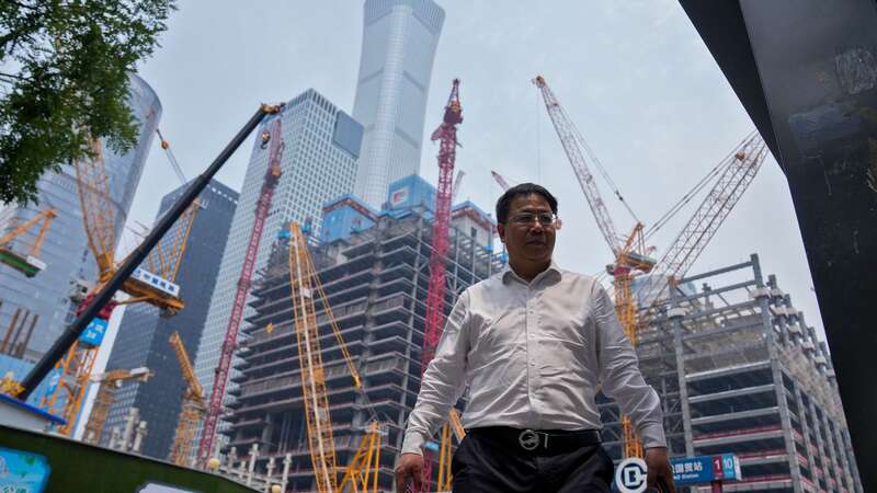 A man walks by a construction site in the Central Business District in Beijing. China