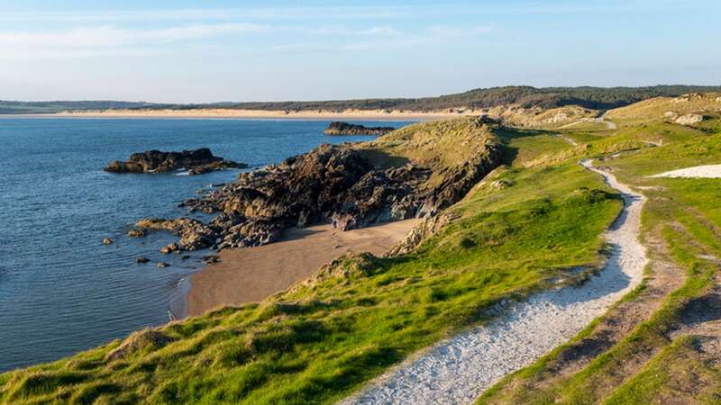 Coast path on Llanddwyn Island with views of Traeth Penrhos on a sunny spring evening (Image: Getty Images)