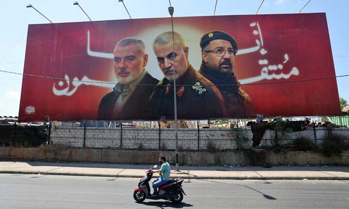 A man rides past a billboard with portraits of slain leaders, Ismail Haniyeh of Hamas, Iranian Quds Force chief Qasem Soleimani (C), and Hezbollah senior commander Fuad Shukr on the road to Beirut airport on 3 August. Photograph: Ibrahim Amro/AFP/Getty Images